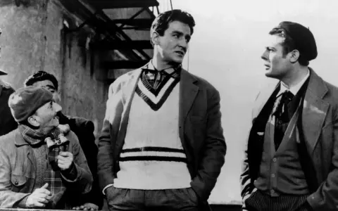 Uomini in abiti d'epoca, uno con un maglione a V, discutono animatamente. Un'iconica scena della commedia all'italiana.