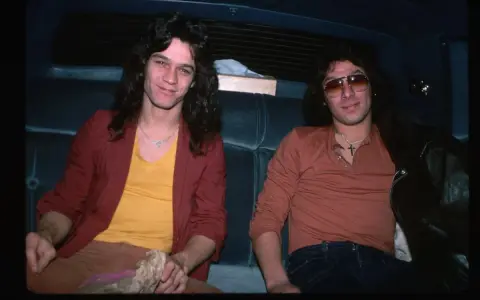 Alex Van Halen i jego brat Eddie Van Halen siedzą w samochodzie, obaj w stylowych ubraniach z lat 80.