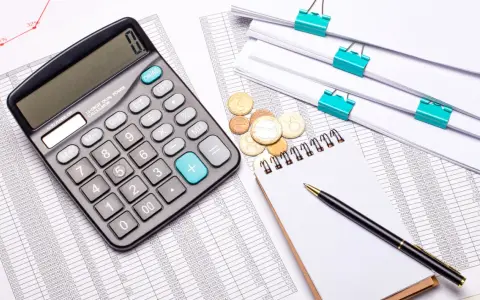 Kalkulator, stosy dokumentów i monety. Czy firma windykacyjna może naliczać odsetki? Analiza finansowa.