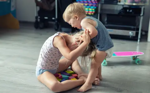 Kleinkind hält älteres Kind am Kopf fest. Was tun, wenn Kinder schlagen? Hier wird spielerisch gestritten.