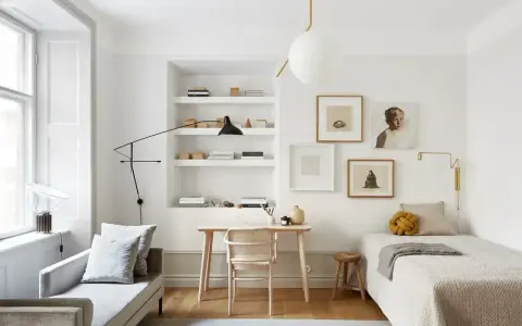 Accogliente camera da letto minimal con letto singolo, scrivania in legno, divanetto e quadri alle pareti.