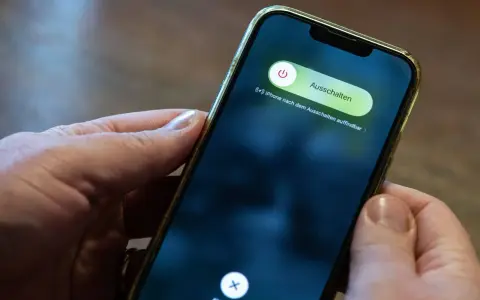 Hände halten ein iPhone mit dem Ausschaltmenü.