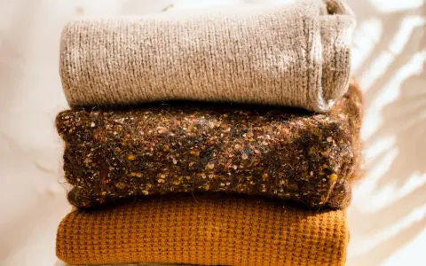 Gestapelte Strickwaren in warmen Herbstfarben. Damit die **Wolle bei 40 Grad waschen** gelingt, sind diese Pullover perfekt.