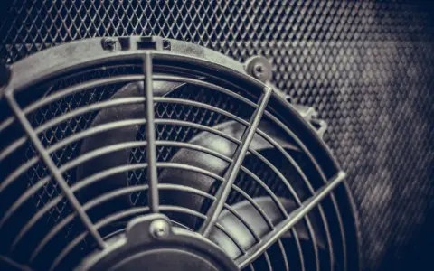 Ventola radiatore non parte, bloccata dietro una griglia metallica. Le pale sono ferme, in attesa di un intervento.