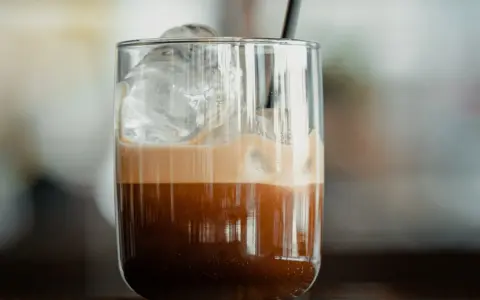 Orzeźwiające freddo espresso z lodem i pianką w szklance, gotowe do wypicia.