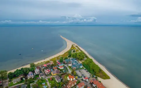 Malownicza miejscowość nad morzem, z domkami i plażą, wcinająca się w spokojne wody.