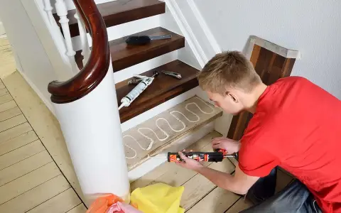 Man lägger lim på en trappsteg för att lägga nytt golv. Trappa inomhus inspiration för ett modernt hem.
