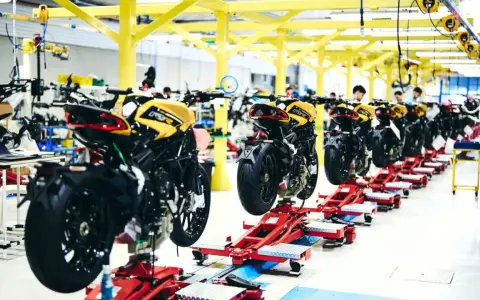 Linea di produzione MV Agusta: moto sportive gialle e nere in fase di assemblaggio su supporti rossi.