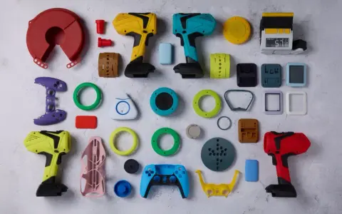 A vibrant collection of components, likely from a color resin 3D printer project, including tool-like objects, game controller parts, and various geometric shapes.