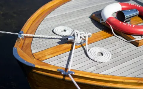 Détail d'une peinture de bateau en bois, avec cordages blancs et une bouée de sauvetage rouge et blanche.