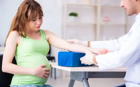 Lekarz pobiera krew od ciężarnej kobiety, aby sprawdzić poziom glukozy w ciąży.