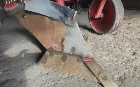Metalowy lemiesz pługa, gotowy do pracy na polu. To właśnie on odwraca ziemię, przygotowując ją pod zasiew.