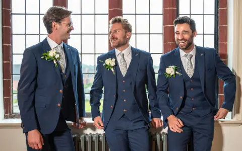 Three groomsmen in navy suits with floral ties and boutonnieres, ready for the usher wedding.