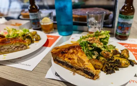 Tranche de pâté en croûte, spécialité Limoges, servie avec salade et pommes de terre rôties.