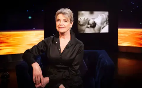 Stina Ekblad sitter i en mörkblå soffa, med en skärm bakom sig som visar klipp från filmer och tv-program med henne.