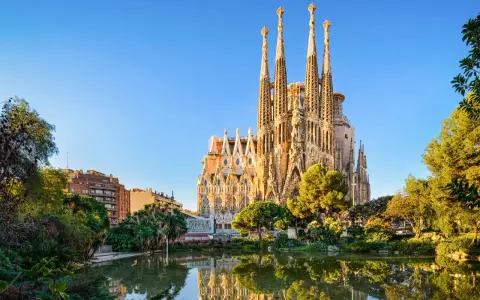 La Sagrada Familia, simbolo di **attività Barcellona**, si specchia in un laghetto circondato da verde.