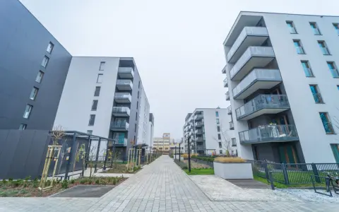 Nowoczesne bloki mieszkalne z balkonami i chodnikiem z kostki brukowej.