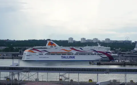 Prom Tallink płynie z Tallinna do Sztokholmu. Statek z kolorowymi pasami na burcie cumuje w porcie.