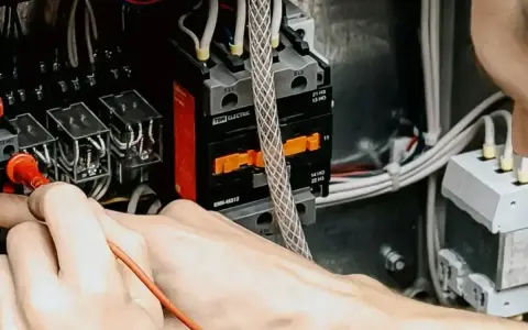 Mani che lavorano su un quadro elettrico, un passo fondamentale per capire come diventare elettricista.