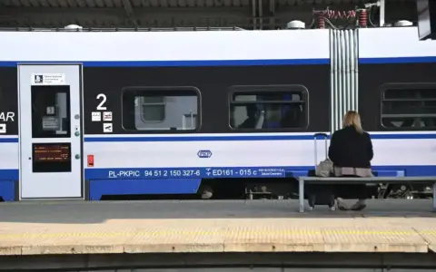 Kobieta z walizką czeka na pociąg PKP Intercity, szukając tanich biletów.