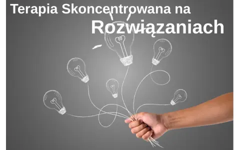 Dłoń trzymająca pęk żarówek narysowanych kredą na szarym tle.