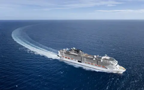 La MSC Virtuosa, con la sua impressionante lunghezza, solca le acque blu lasciando una scia bianca.