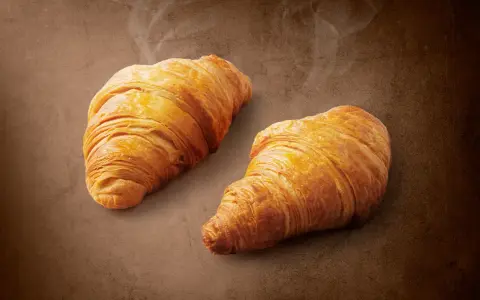 Dwa złociste croissanty z nadzieniem orzechowym z Lidla, parujące delikatnie. Idealne na śniadanie, zaspokoją głód i dostarczą energii.