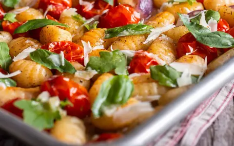 Gebackene Gnocchi mit Kirschtomaten, Basilikum und Parmesan. So sehen köstliche Gnocchi aus, wenn sie im Ofen mit frischen Zutaten zubereitet werden.