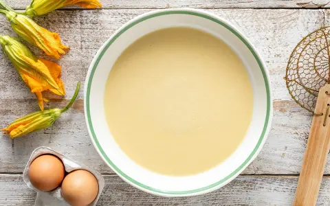 Pastella per fiori di zucca pronta in ciotola, con fiori freschi e uova a lato.