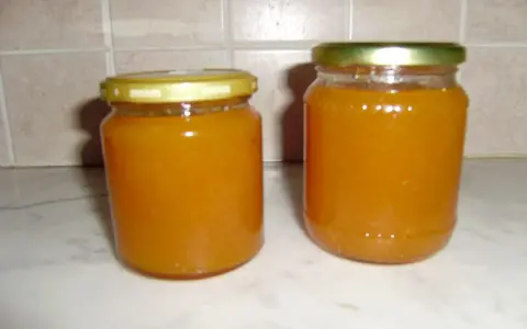 Due barattoli di marmellata di pesche fatti in casa, pronti per essere gustati.