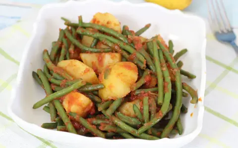 Fagiolini in umido con patate, un piatto saporito e colorato, servito in una ciotola bianca su una tovaglia a quadri.