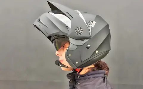 Profilo di una persona con casco da moto modulare nero, visiera sollevata e microfono. Guida sicura: come scegliere casco moto.