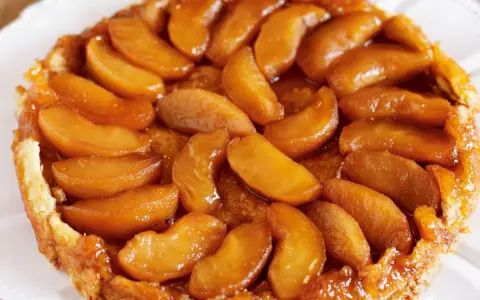 En gyllene tarte tatin med karamelliserade äppelklyftor som glänser. En klassisk fransk dessert som smälter i munnen.