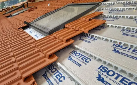 Tegole in laterizio su un tetto in costruzione, con lucernario e isolamento termoisolante ISOTEC.