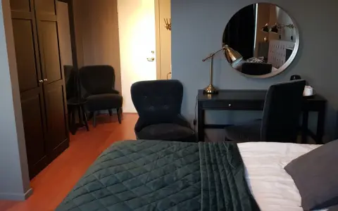 Ett modernt rum på Haparanda Stadshotell med en stor säng, skrivbord, spegel och bekväma fåtöljer.