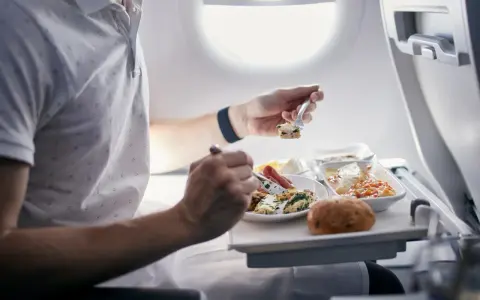 Pasażer je posiłek na pokładzie samolotu. Zastanawiasz się, czy można przewozić jedzenie w bagażu rejestrowanym Ryanair?