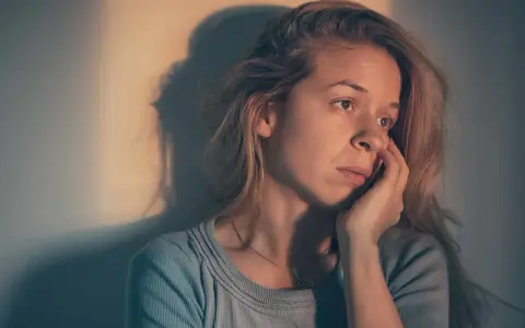 Une femme songeuse, le regard perdu, se demande : "suis je sous l'emprise d'un manipulateur test ?" Son visage exprime le doute et l'inquiétude.