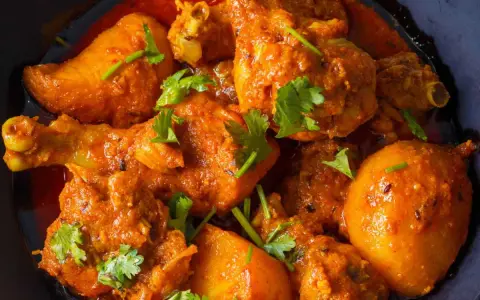 Un plat appétissant de poulet et de pommes de terre en sauce curry, garni de coriandre fraîche. Un délice pour les amateurs de marinade poulet curry.