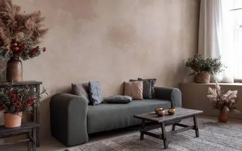 Gemütliches Wohnzimmer mit Sofa, Holztisch und rustikalen Dekorationen vor einer Wand mit **lime wash**-Oberfläche.