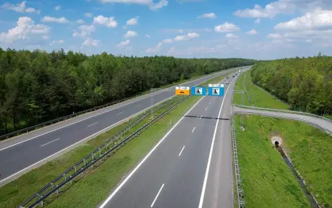 Znaki na autostradzie A4 informują, czy jest ona płatna. Widok na pustą autostradę w słoneczny dzień.