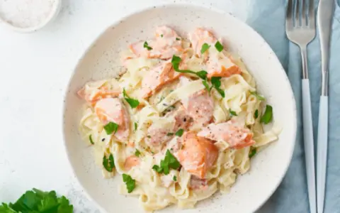 Pasta cremosa con trozos de salmón rosado y perejil fresco. Un plato delicioso y nutritivo.