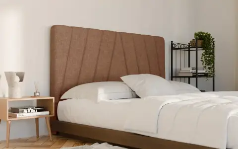 Un letto in tessuto marrone con testiera imbottita, lenzuola bianche e comodino in legno. Ideale per chi cerca consigli su come pulire letto in tessuto.