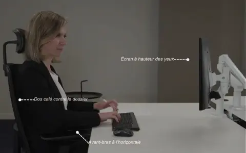 Une femme assise, respectant la règle ergonomique : dos calé, avant-bras à l'horizontale, écran à hauteur des yeux.