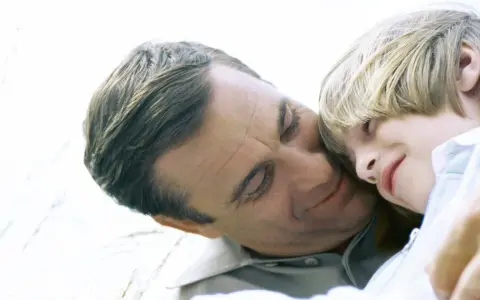 Vater und Kind kuscheln. Auch bei getrennt lebenden Eltern ist die Haftpflichtversicherung wichtig für den Nachwuchs.