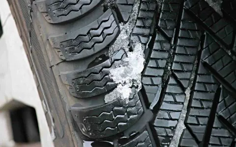 Gomme invernali con neve e ghiaccio incastrati nel battistrada. Le gomme screpolate battistrada mostrano segni di usura, ma ancora funzionali.