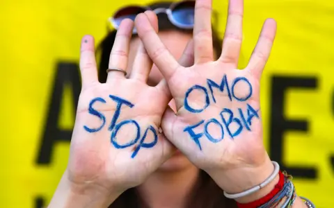 Mani con scritto "STOP OMOSESSUALITÀ" in blu, un messaggio contro il bullismo omofobico.