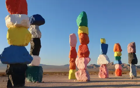 Les **seven magic mountains** illuminent le désert. Des rochers colorés empilés créent une œuvre d'art vibrante sous un ciel bleu.