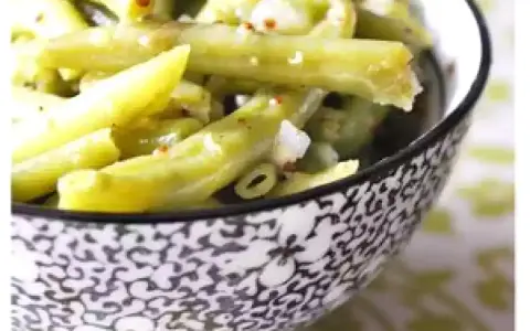 Salade de haricots verts croquants, assaisonnée et parsemée de quelques épices rouges, servie dans un bol décoratif.