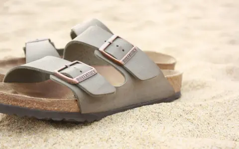 Sandali Birkenstock grigi sulla sabbia. Scopri come si lavano le Birkenstock per mantenerle perfette.