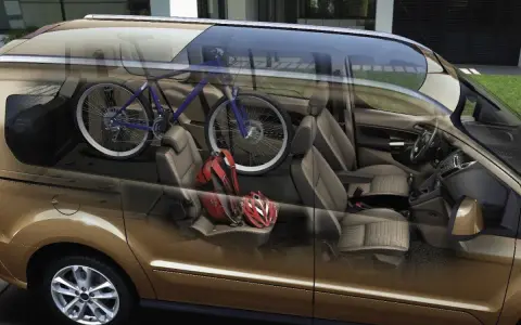 Interior de furgoneta con bicicleta azul y cascos rojos. ¡Cuidado con la multa por llevar bici dentro del coche!